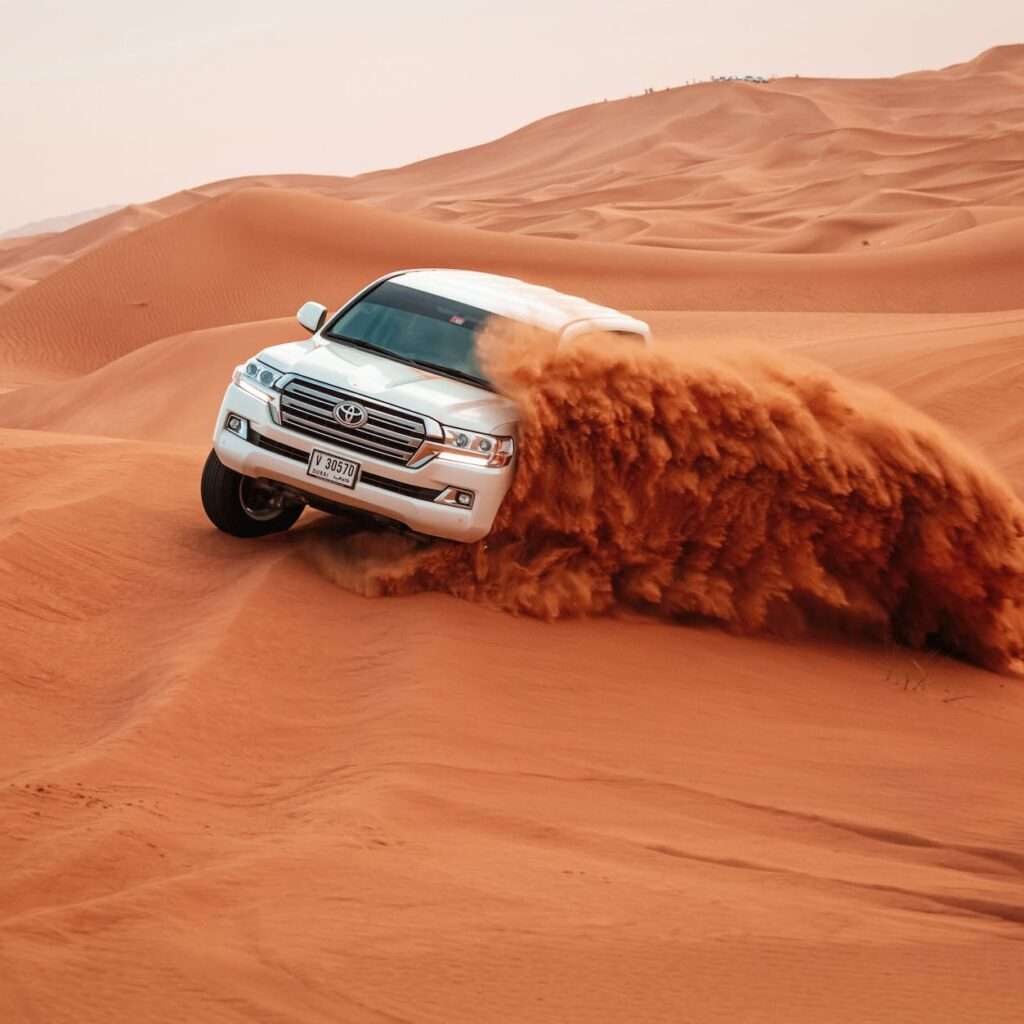 white toyota car driving on sand dunes